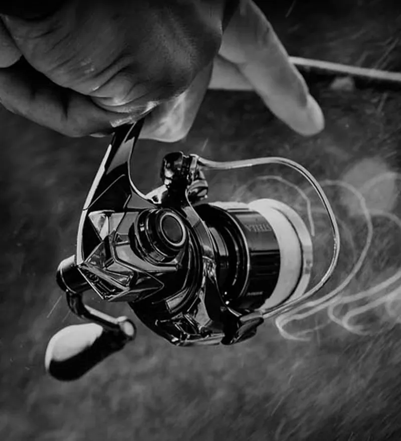 Carrete de spinning en blanco y negro con el hilo en movimiento